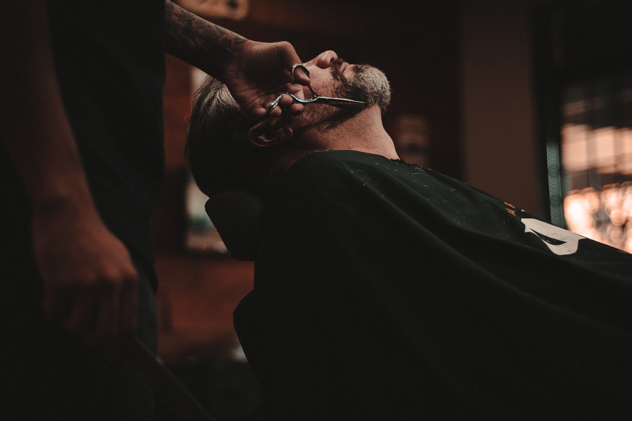 Peluquero cortando la barba a cliente